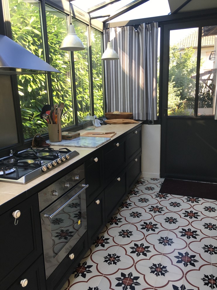パリにある中くらいなコンテンポラリースタイルのおしゃれなキッチン (シングルシンク、インセット扉のキャビネット、黒いキャビネット、大理石カウンター、黒いキッチンパネル、シルバーの調理設備、セメントタイルの床、マルチカラーの床) の写真