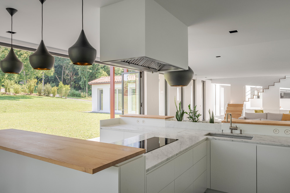 Design ideas for a scandi open plan kitchen with flat-panel cabinets, white cabinets, marble worktops, an integrated sink, white splashback, marble splashback, stainless steel appliances, multiple islands, grey floors and white worktops.