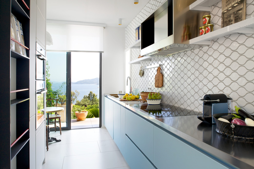 Cette image montre une cuisine américaine linéaire design de taille moyenne avec des portes de placard bleues et une crédence beige.
