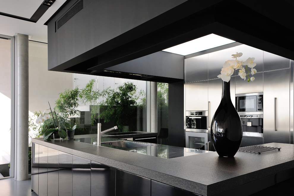 Idéer för ett mellanstort modernt kök, med en integrerad diskho, skåp i rostfritt stål, rostfria vitvaror och en köksö