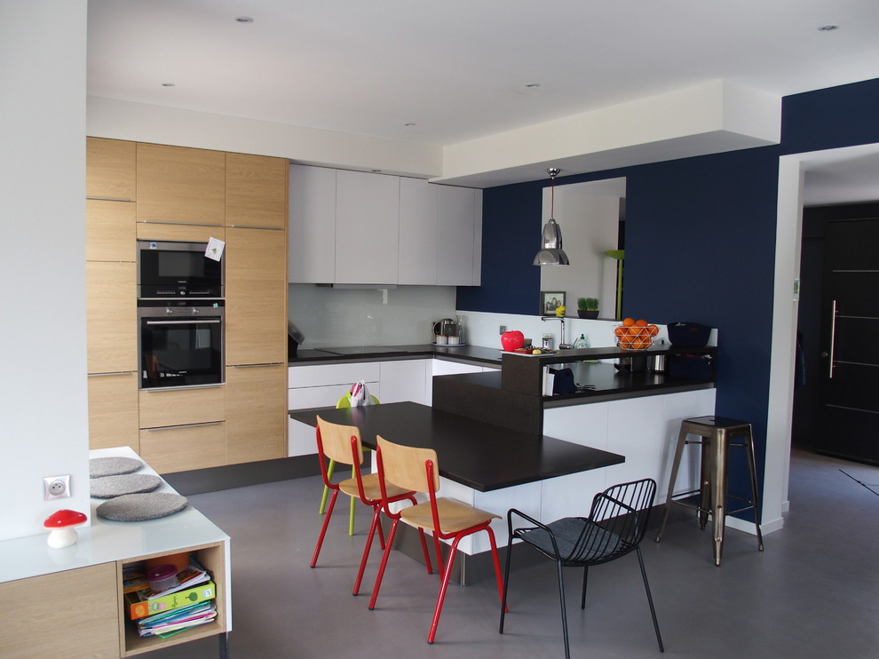 Exempel på ett mellanstort modernt kök, med en undermonterad diskho, luckor med profilerade fronter, skåp i rostfritt stål, laminatbänkskiva, svart stänkskydd, stänkskydd i travertin, rostfria vitvaror, travertin golv, en köksö och grått golv