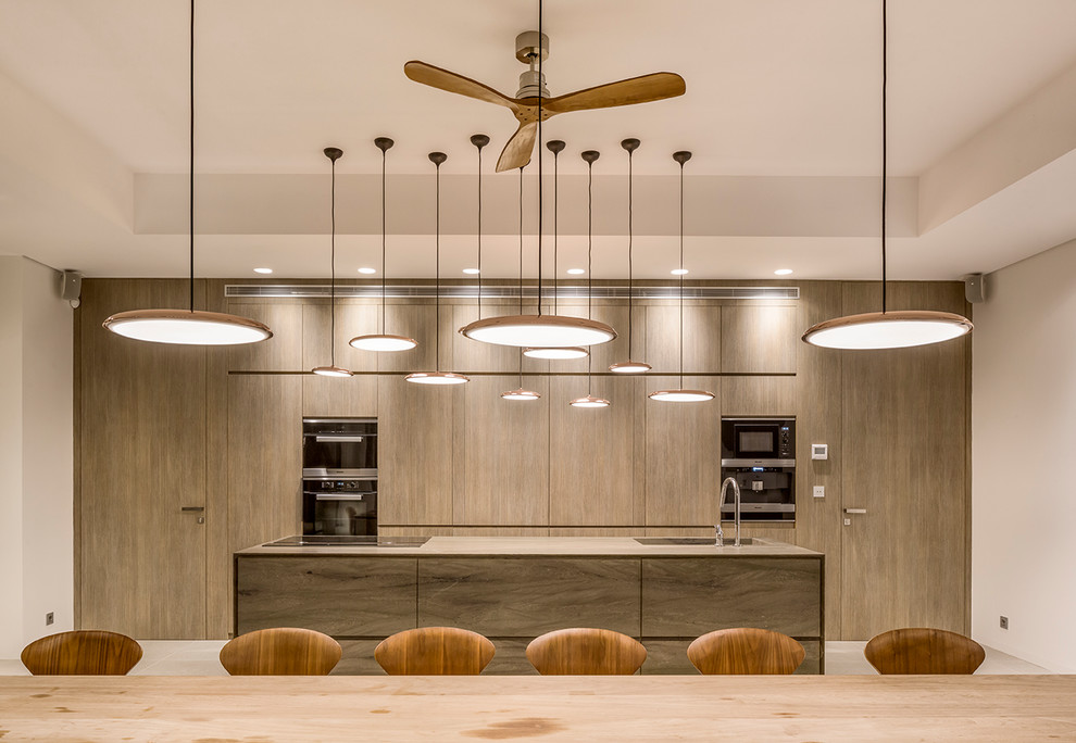 Foto di una grande cucina contemporanea con lavello integrato, elettrodomestici neri, ante lisce, ante in legno scuro e top marrone