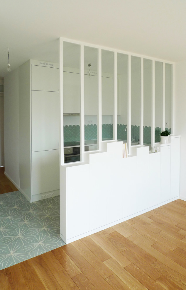 This is an example of a small contemporary u-shaped open plan kitchen in Paris with a submerged sink, flat-panel cabinets, white cabinets, quartz worktops, green splashback, ceramic splashback, integrated appliances, cement flooring, no island, turquoise floors and white worktops.