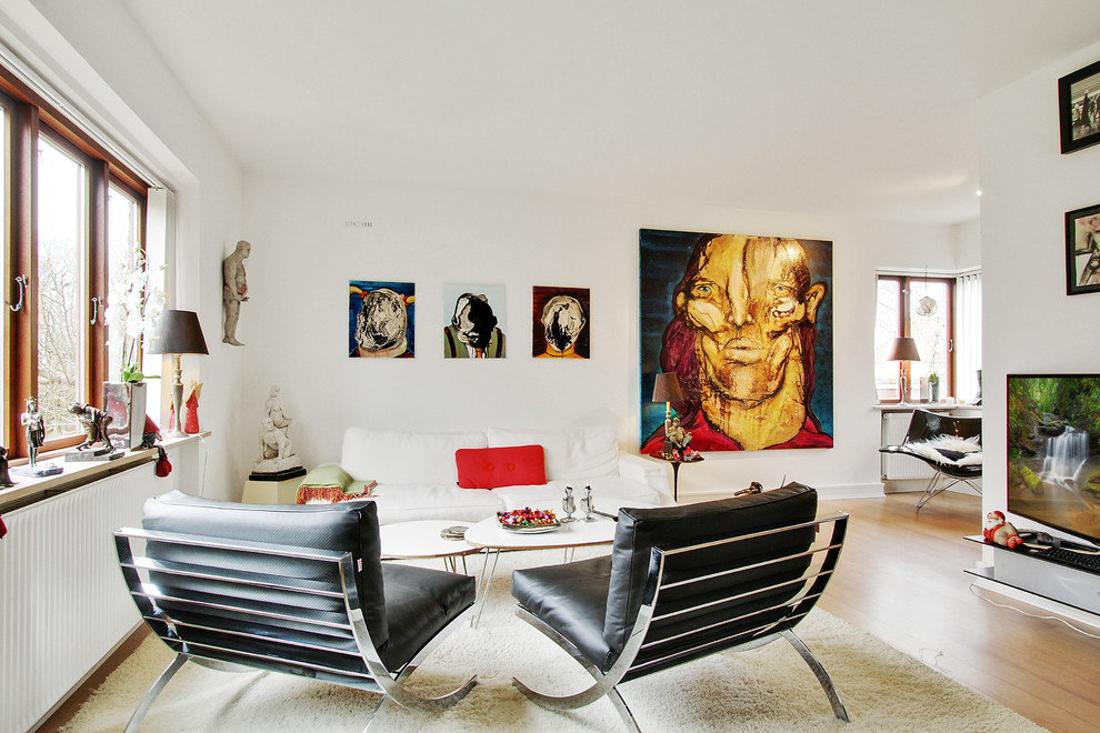 Modelo de salón para visitas cerrado minimalista de tamaño medio sin chimenea con paredes blancas, suelo de madera clara y televisor colgado en la pared