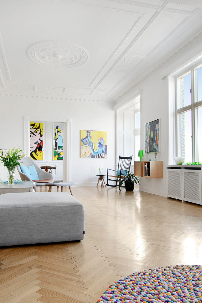 На фото: большая гостиная комната в скандинавском стиле с белыми стенами и светлым паркетным полом