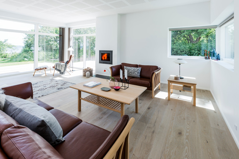 Immagine di un grande soggiorno scandinavo chiuso con pareti bianche, parquet chiaro, nessuna TV, sala formale, stufa a legna e cornice del camino in mattoni