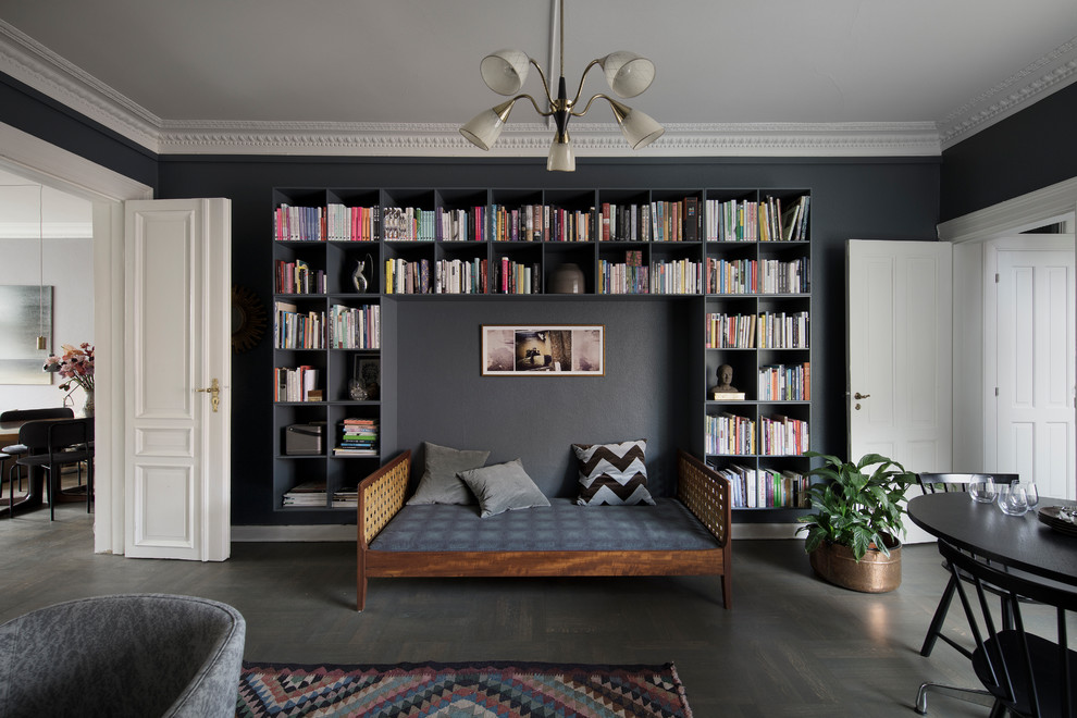 Cette image montre un salon nordique ouvert avec une bibliothèque ou un coin lecture, un mur noir, parquet foncé et un sol noir.