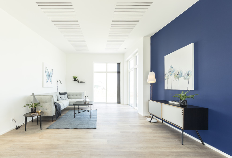 Immagine di un grande soggiorno minimalista chiuso con pareti blu, parquet chiaro e nessuna TV