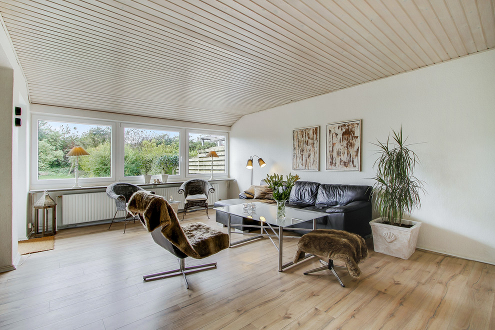 Immagine di un soggiorno scandinavo aperto con pareti bianche, pavimento in laminato e nessun camino