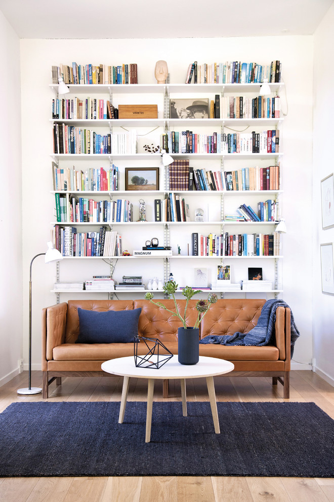 Example of a mid-sized danish enclosed light wood floor living room library design in Copenhagen with white walls and no tv