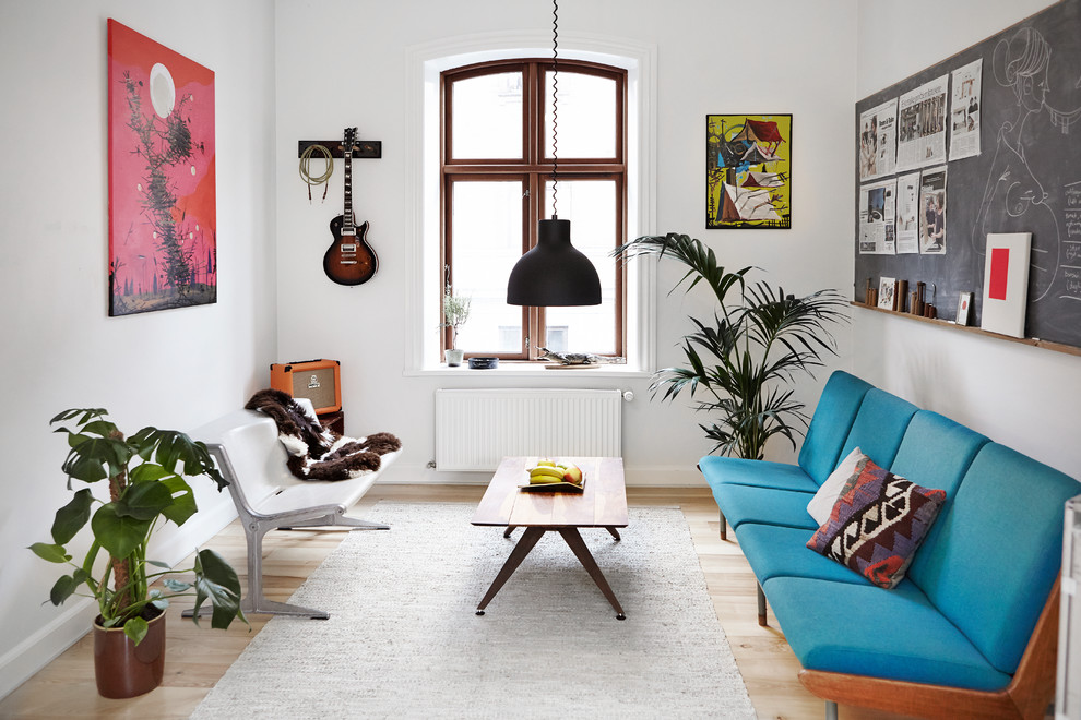 Источник вдохновения для домашнего уюта: изолированная гостиная комната в скандинавском стиле с белыми стенами, светлым паркетным полом и синим диваном без телевизора