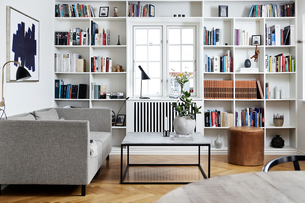 Exemple d'un petit salon scandinave fermé avec une bibliothèque ou un coin lecture, un mur blanc, aucune cheminée, un sol beige et parquet clair.