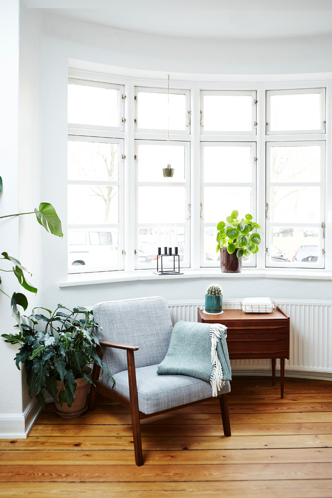 Imagen de salón cerrado escandinavo con paredes blancas y suelo de madera en tonos medios