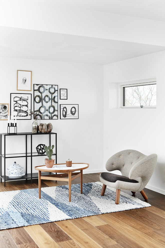 Idéer för att renovera ett minimalistiskt vardagsrum, med vita väggar och mellanmörkt trägolv