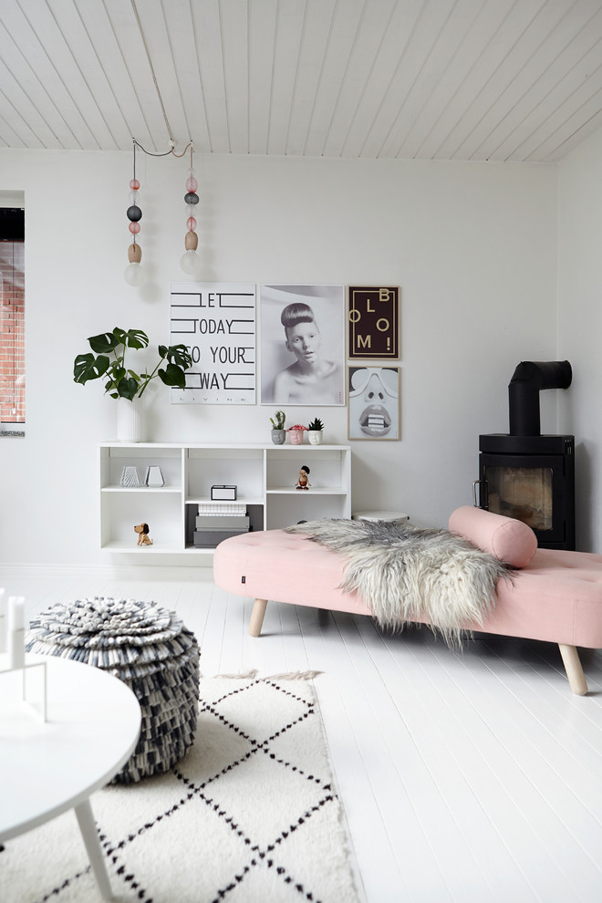 Idée de décoration pour un salon nordique avec un mur blanc, parquet peint et un poêle à bois.