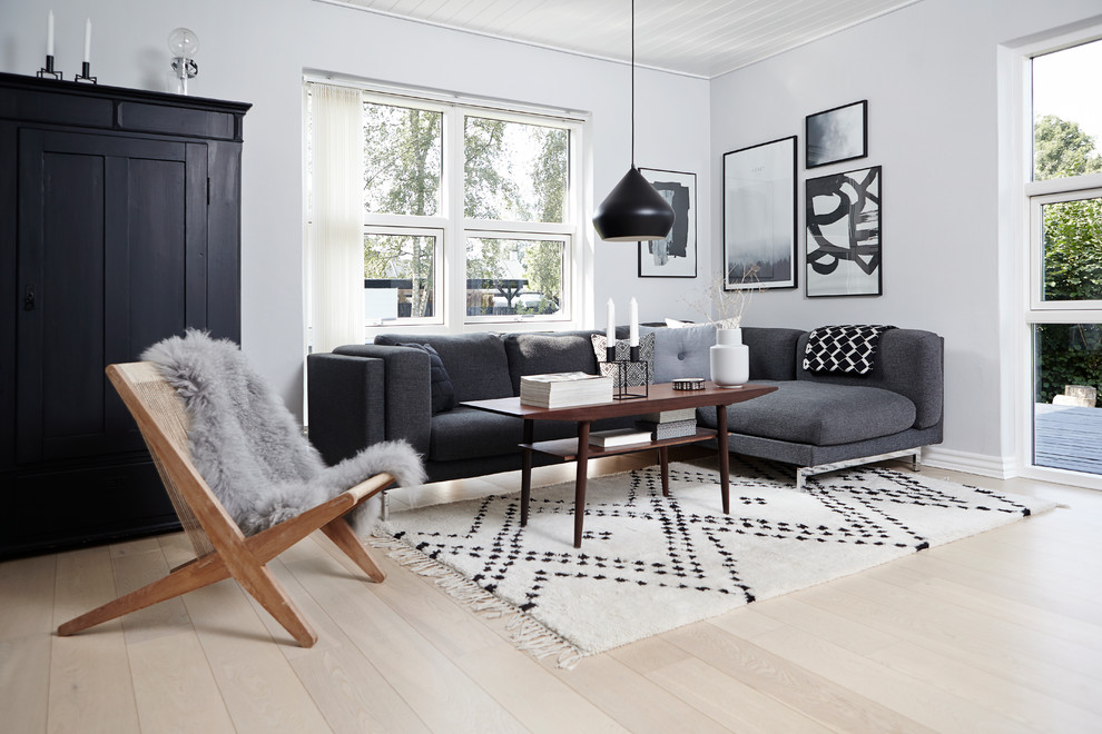 На фото: изолированная гостиная комната в скандинавском стиле с белыми стенами и светлым паркетным полом