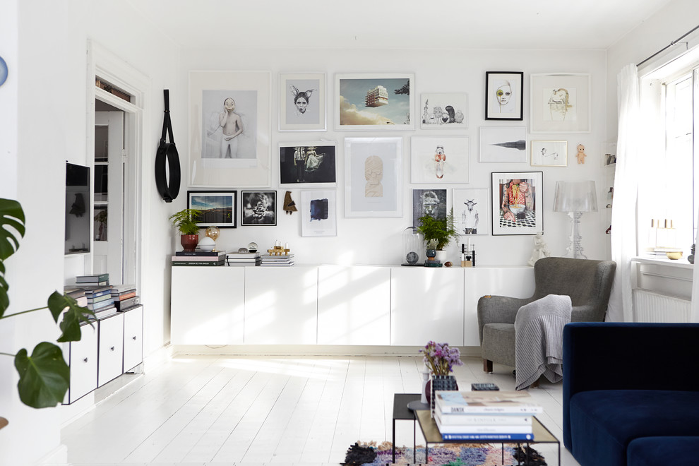 Cette image montre un salon nordique de taille moyenne avec un mur blanc, parquet peint, un téléviseur fixé au mur et éclairage.