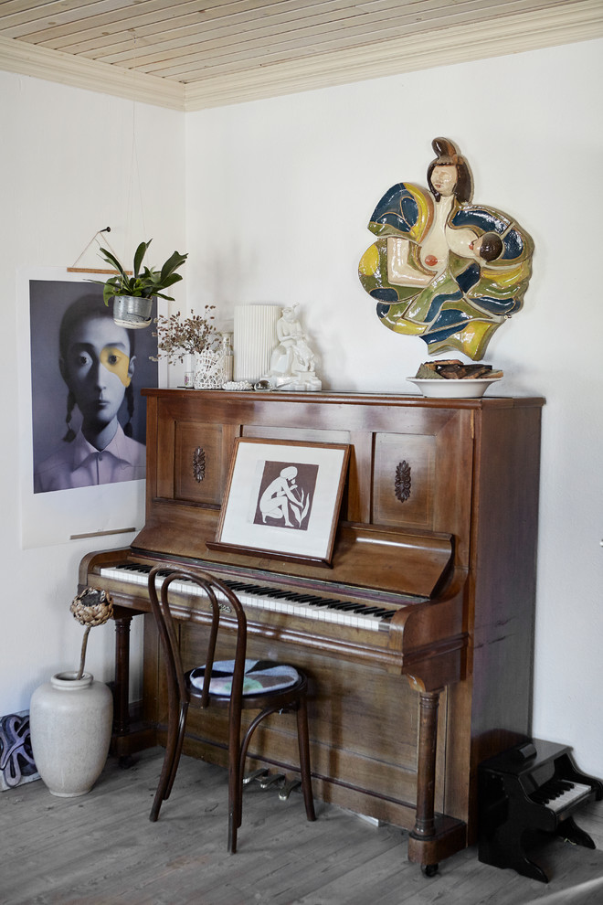 Diseño de salón con rincón musical bohemio con paredes blancas y suelo de madera oscura