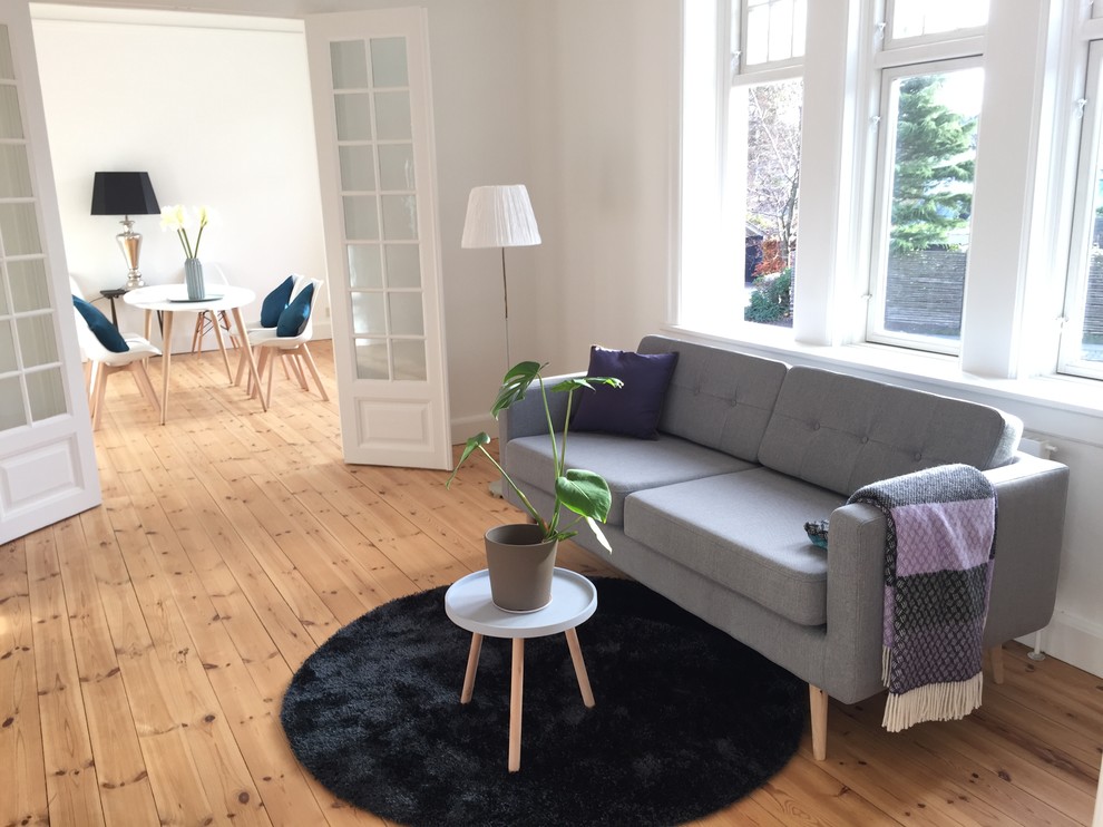 This is an example of a medium sized scandinavian formal enclosed living room in Other with white walls, medium hardwood flooring, no fireplace and no tv.
