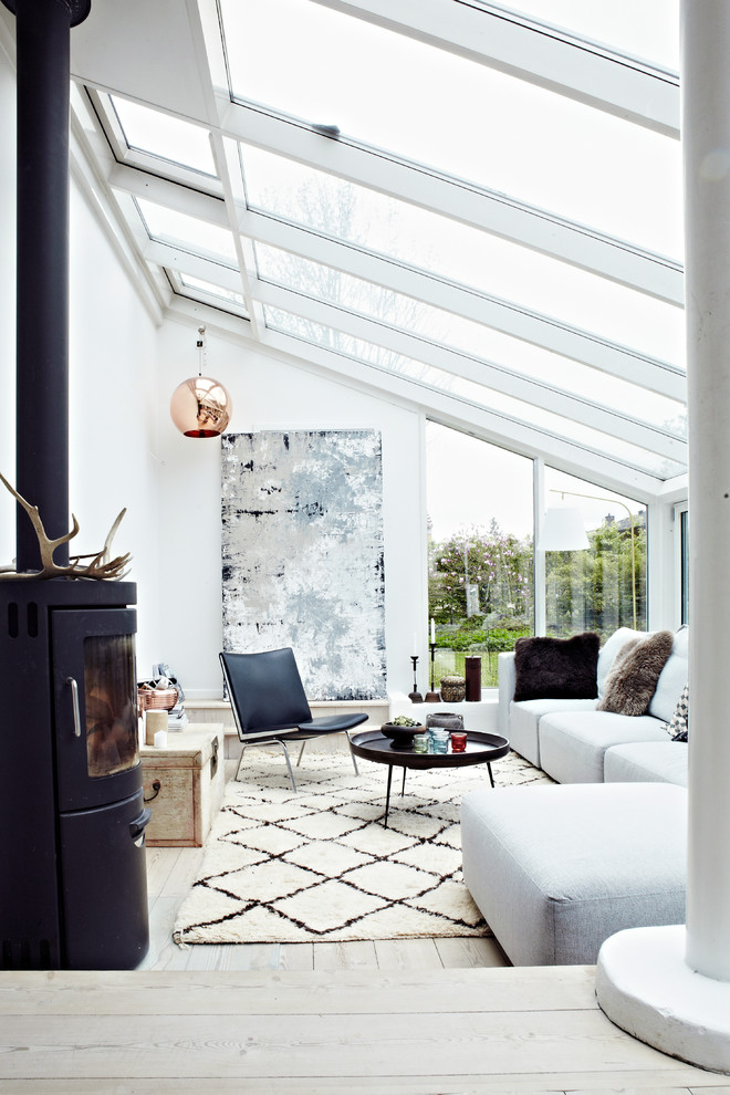 Fernseherloses Skandinavisches Wohnzimmer mit weißer Wandfarbe, hellem Holzboden und Kaminofen in Sonstige