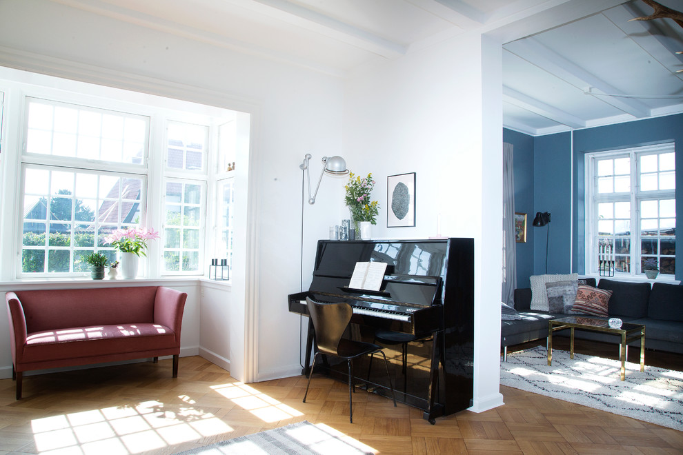 Источник вдохновения для домашнего уюта: гостиная комната в скандинавском стиле с с книжными шкафами и полками, белыми стенами и паркетным полом среднего тона