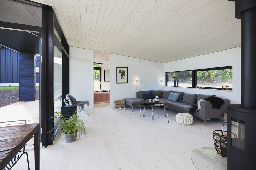 Mittelgroßes, Offenes Skandinavisches Wohnzimmer mit weißer Wandfarbe, gebeiztem Holzboden und weißem Boden in Kopenhagen