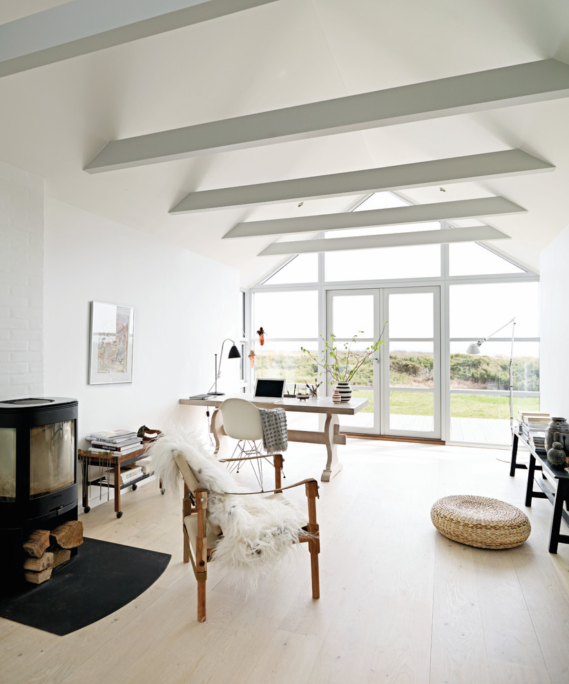 Foto de salón para visitas abierto nórdico de tamaño medio sin televisor con paredes blancas, suelo de madera clara, estufa de leña y marco de chimenea de metal