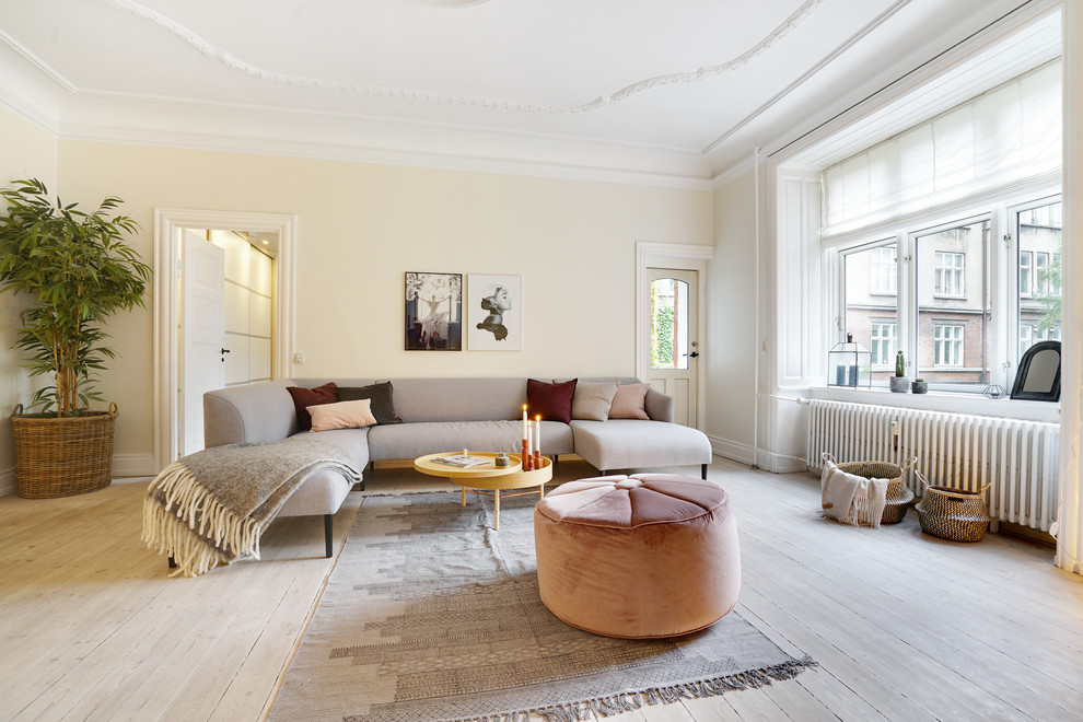 This is an example of a large scandinavian enclosed living room in Copenhagen with light hardwood flooring, no fireplace, beige walls and beige floors.