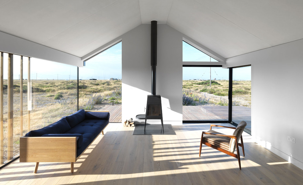 Foto di un soggiorno minimalista con pareti bianche, parquet chiaro, stufa a legna e pavimento beige
