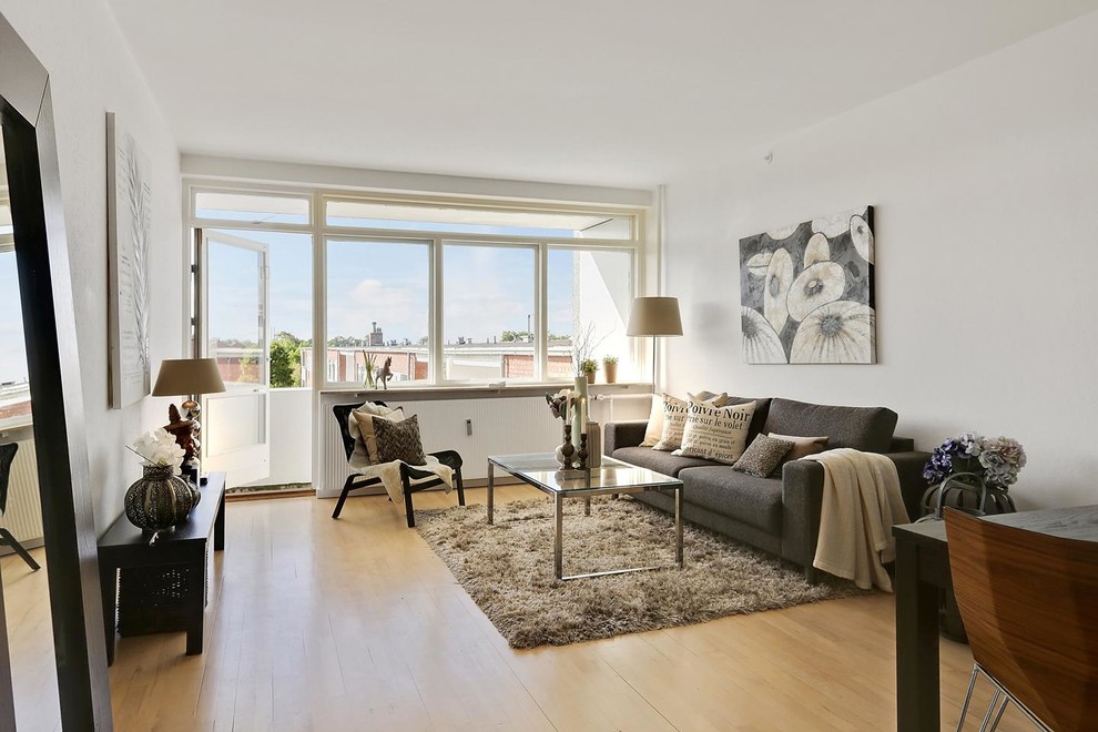 Inspiration for a scandi open plan living room in Copenhagen with white walls, medium hardwood flooring and brown floors.
