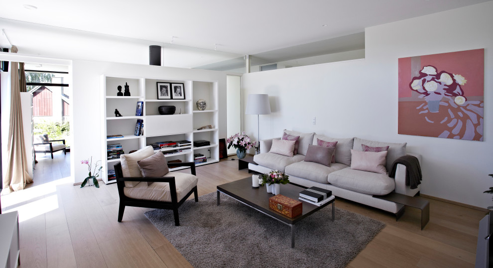 Aménagement d'un salon contemporain de taille moyenne et fermé avec un mur blanc, un sol en bois brun et un téléviseur dissimulé.