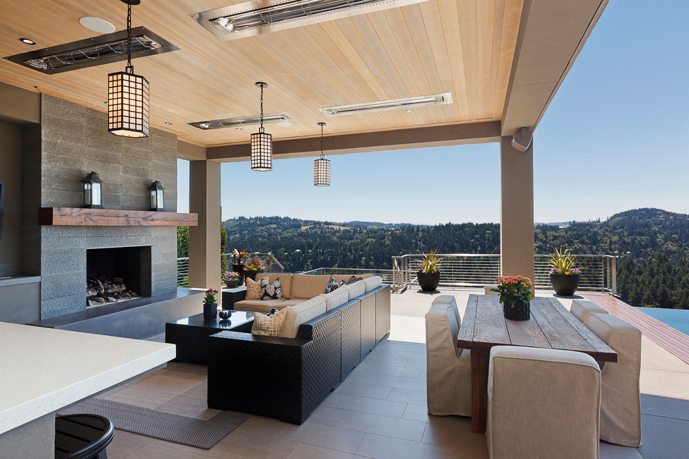 Idee per una grande terrazza contemporanea dietro casa con un tetto a sbalzo e un caminetto