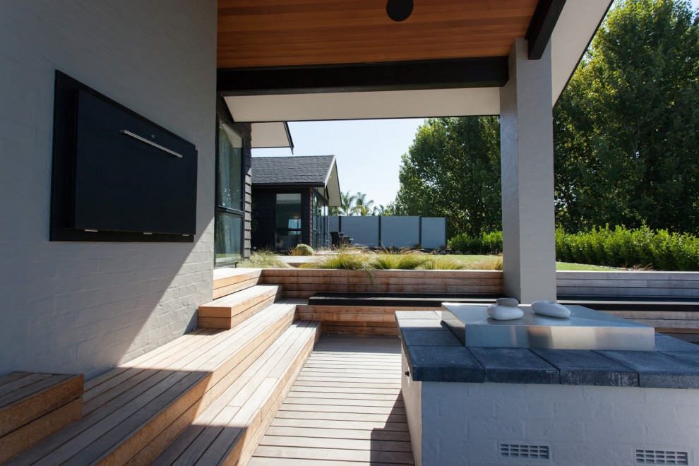 Idées déco pour une grande terrasse arrière moderne avec un foyer extérieur et une extension de toiture.