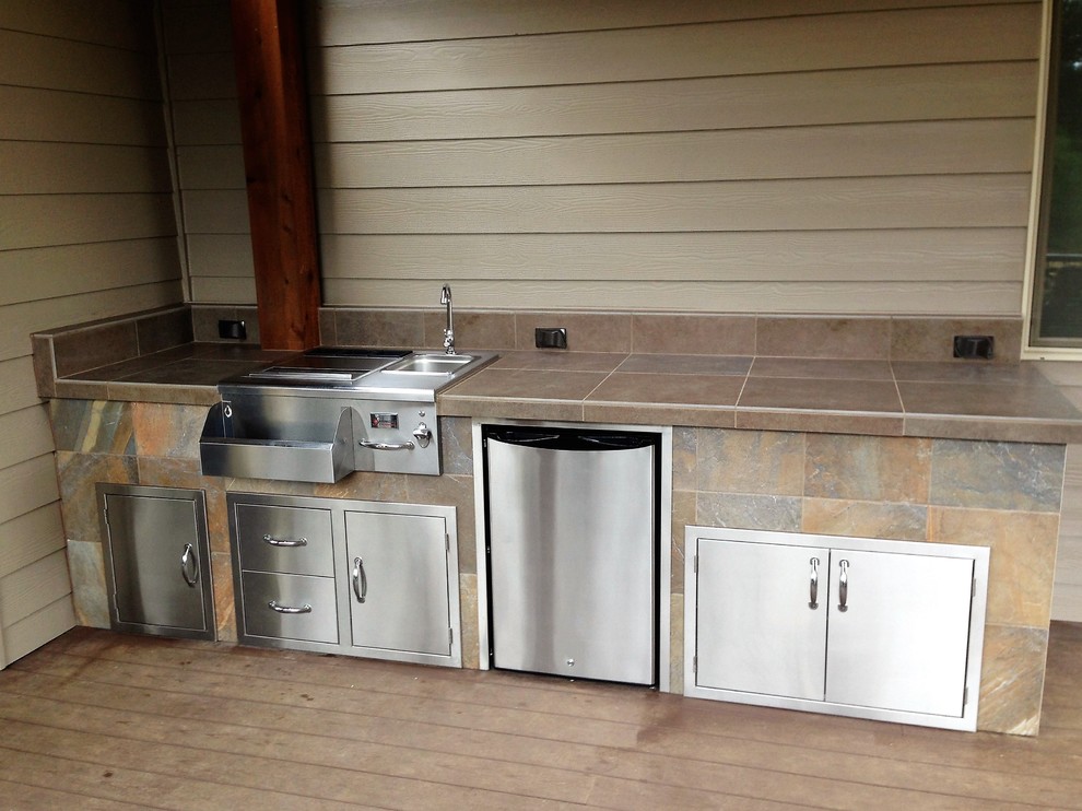 Trendy backyard outdoor kitchen deck photo in Portland with a roof extension