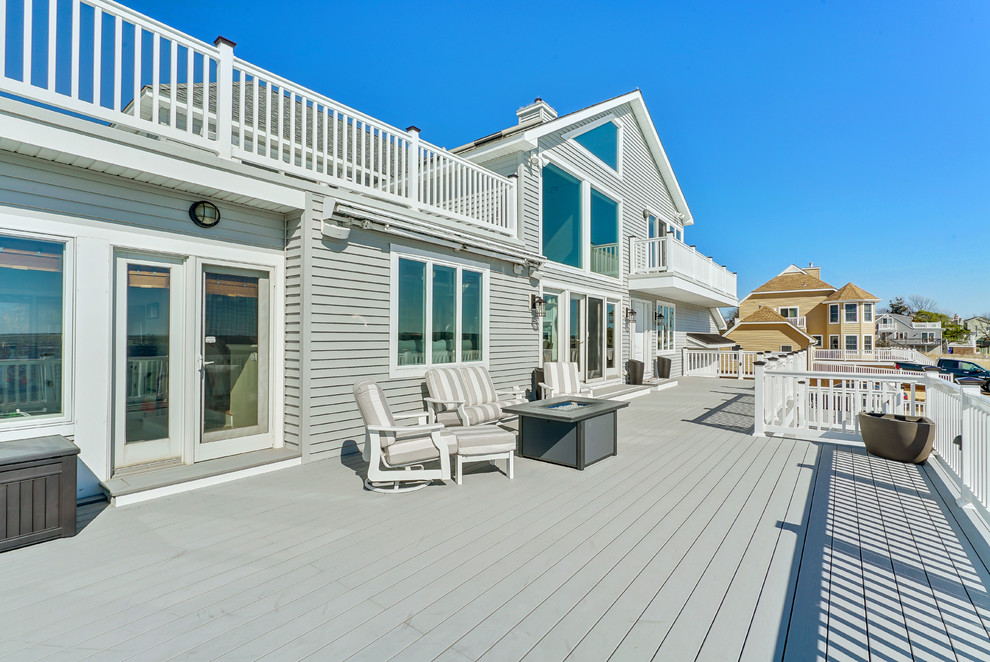 Example of a large beach style backyard deck design in New York with no cover