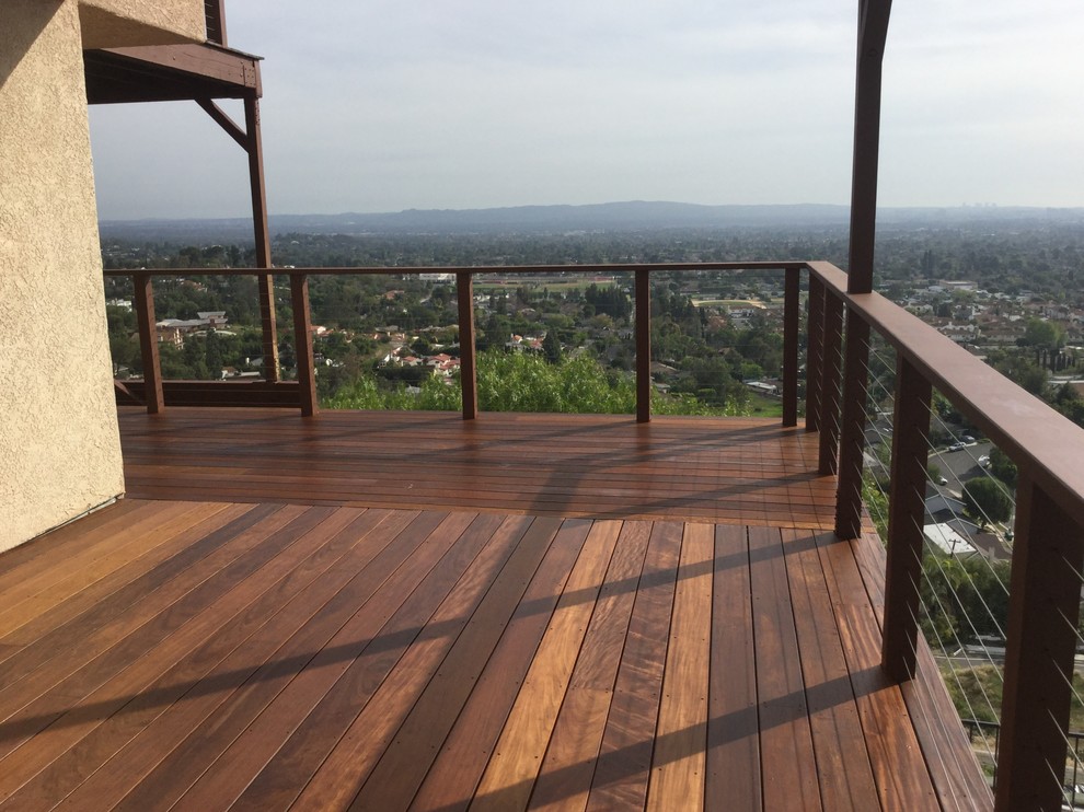 Example of a large minimalist backyard deck design in Orange County with no cover