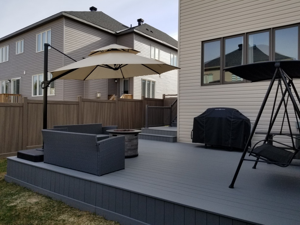 Inspiration for a large modern backyard deck remodel in Ottawa with a fire pit