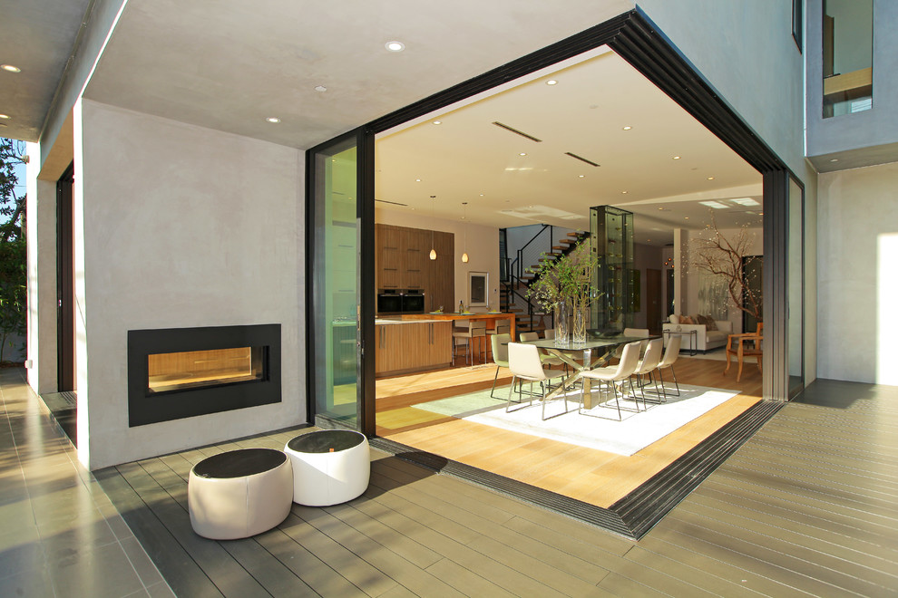 Réalisation d'une terrasse design avec un foyer extérieur et une extension de toiture.