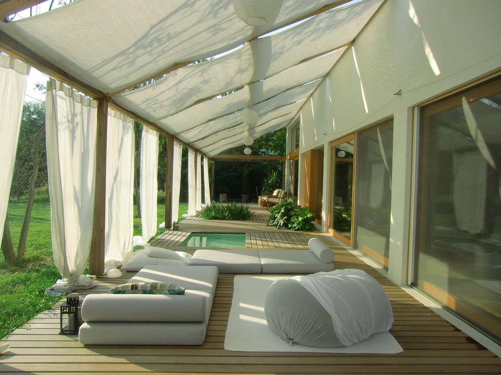 Imagen de terraza minimalista grande con toldo y iluminación