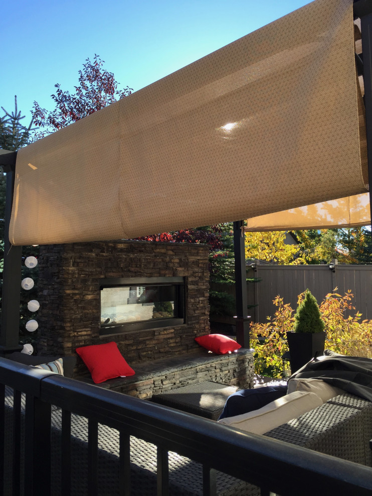 Immagine di una terrazza di medie dimensioni e dietro casa con un caminetto e un parasole