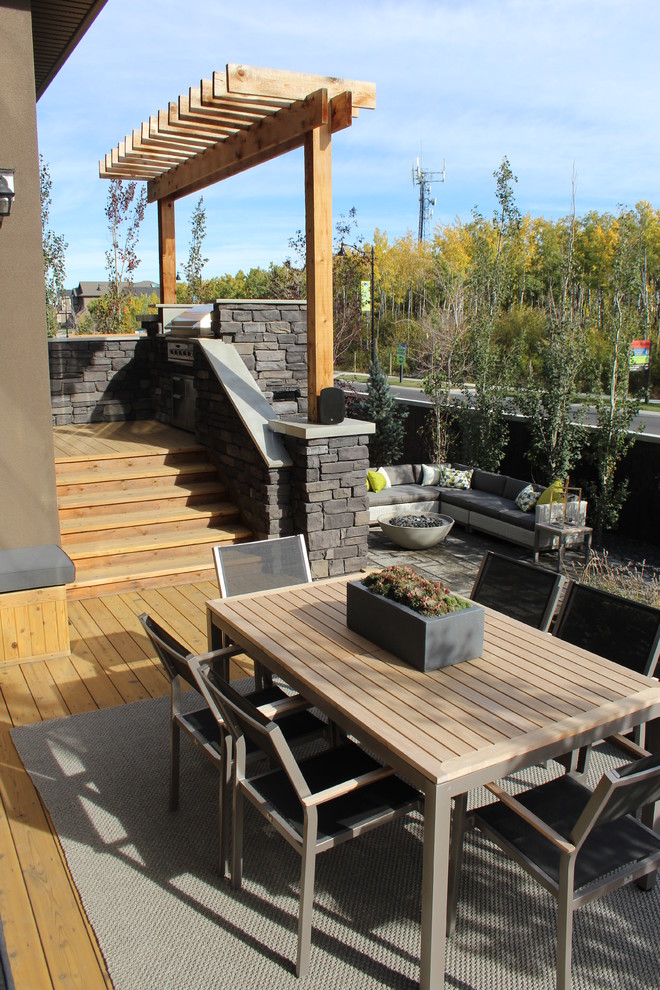 This is an example of a small contemporary back terrace in Calgary with an outdoor kitchen and a pergola.