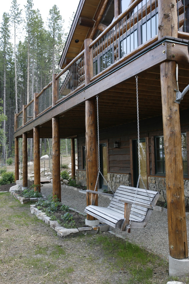 Cette image montre une grande terrasse arrière chalet avec une extension de toiture.