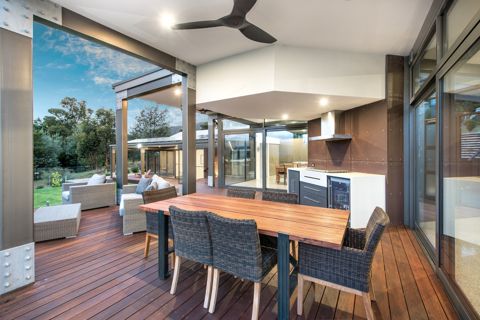Réalisation d'une très grande terrasse latérale design avec une cuisine d'été et une extension de toiture.