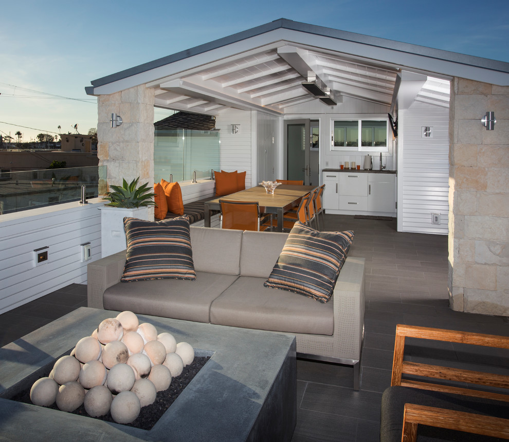 Deck - large coastal rooftop deck idea in Orange County with a fire pit and a roof extension