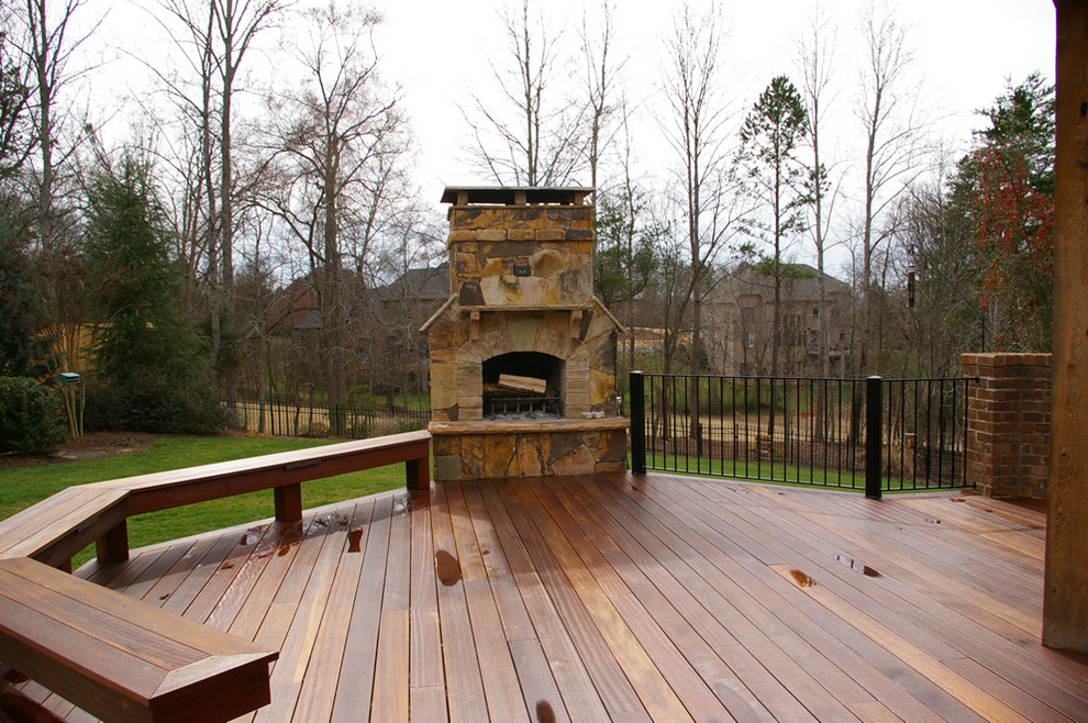 Inspiration for a large rustic backyard deck remodel in Charlotte with a fire pit and a roof extension