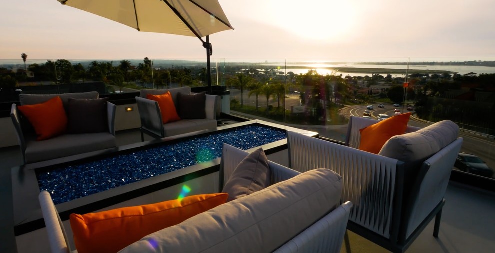 This is an example of a large modern roof terrace in San Diego with a fire feature and an awning.