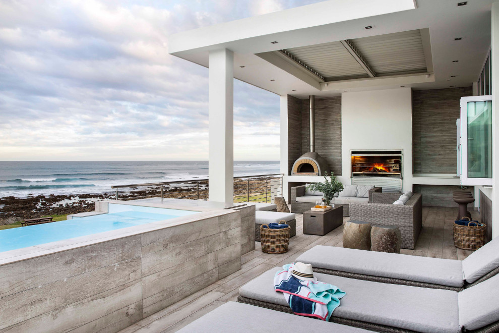 Photo of a large beach style back terrace in Other with a fireplace and a roof extension.