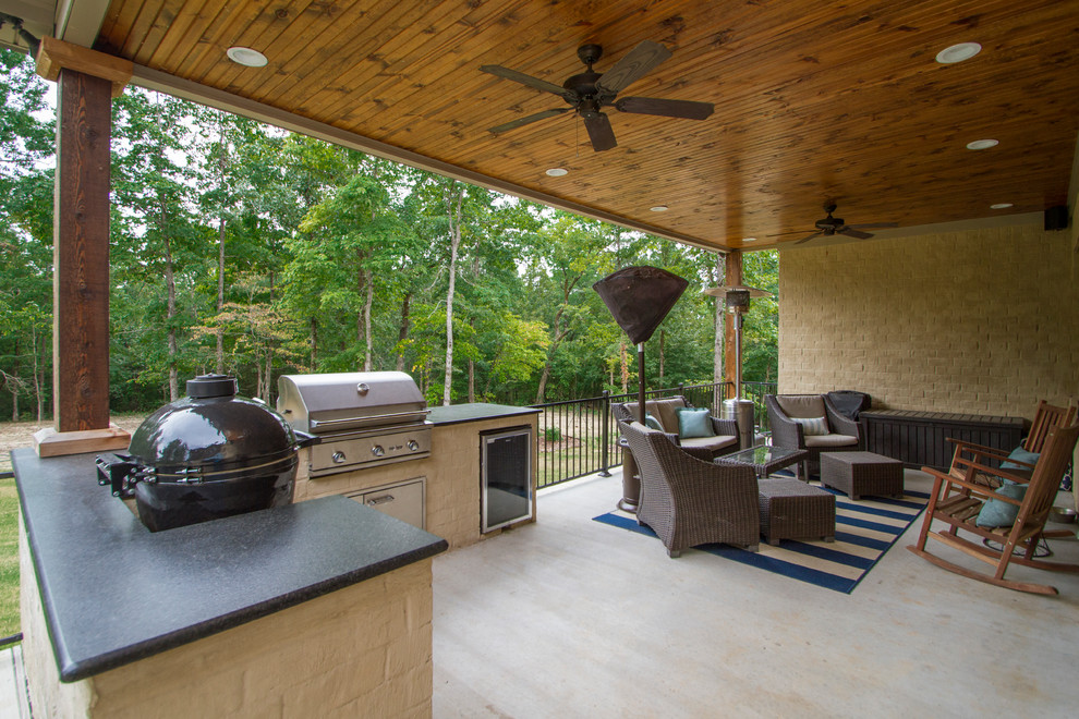 Cette image montre une grande terrasse arrière traditionnelle avec une cuisine d'été et une extension de toiture.