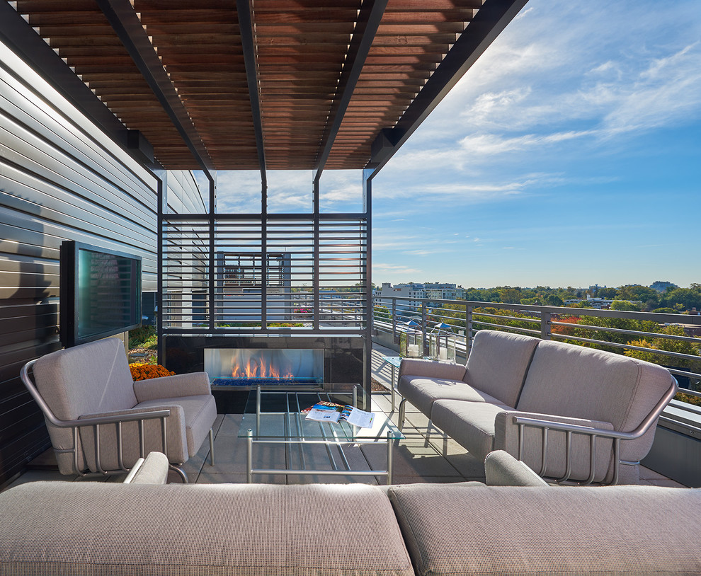 Cette image montre une terrasse latérale design de taille moyenne avec un foyer extérieur et une extension de toiture.