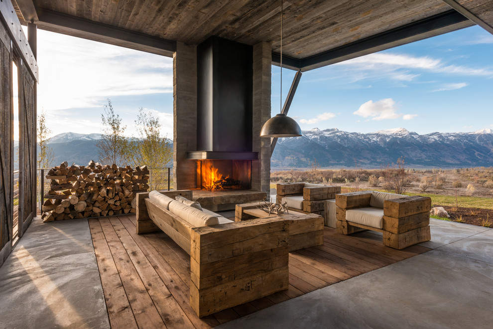 Aménagement d'une terrasse montagne avec un foyer extérieur et une extension de toiture.